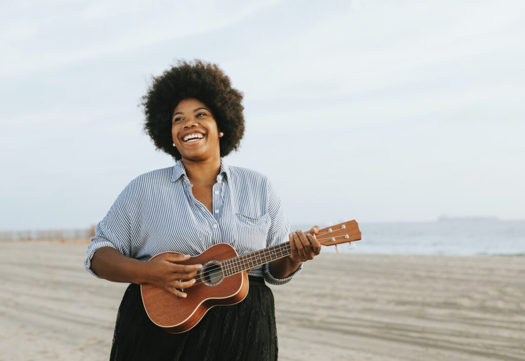 African American musician playing ukulele at the beach